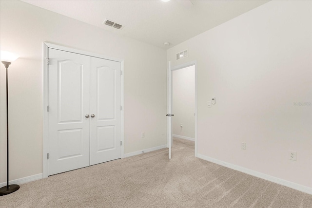 unfurnished bedroom with a closet and light carpet