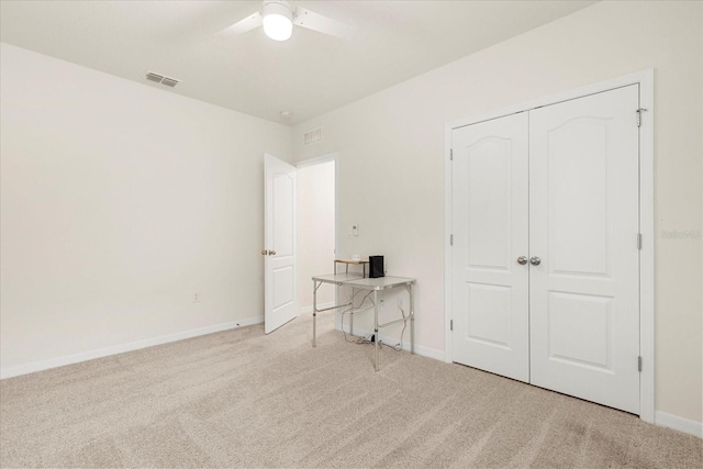 unfurnished bedroom with ceiling fan, light colored carpet, and a closet