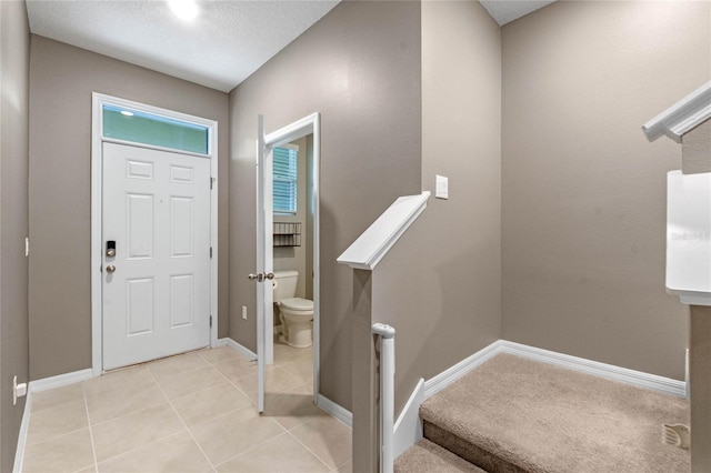 foyer with a textured ceiling and light tile patterned floors