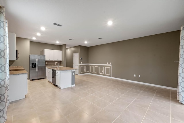 kitchen featuring an island with sink, appliances with stainless steel finishes, light tile patterned flooring, white cabinets, and sink