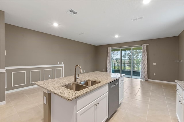 kitchen with a center island with sink, stainless steel dishwasher, white cabinets, light stone counters, and sink