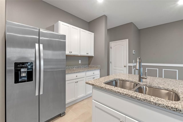 kitchen with sink, light tile patterned flooring, white cabinetry, light stone countertops, and stainless steel fridge with ice dispenser