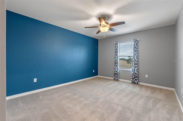 spare room with ceiling fan, a textured ceiling, and light carpet