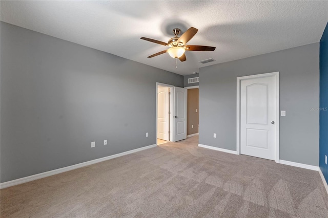 unfurnished bedroom with light carpet, ceiling fan, and a textured ceiling