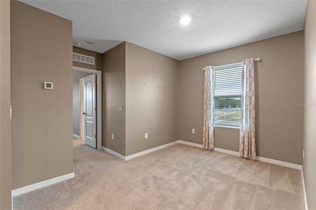 unfurnished room with light colored carpet and a textured ceiling