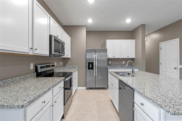 kitchen featuring light tile patterned floors, stainless steel appliances, a kitchen island with sink, white cabinets, and sink