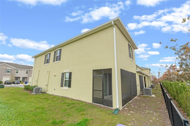 rear view of house featuring a lawn, cooling unit, and a sunroom