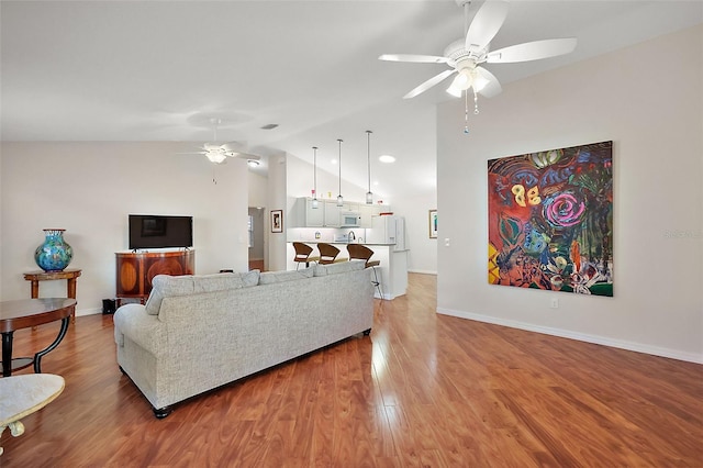 living room with ceiling fan, wood-type flooring, and vaulted ceiling