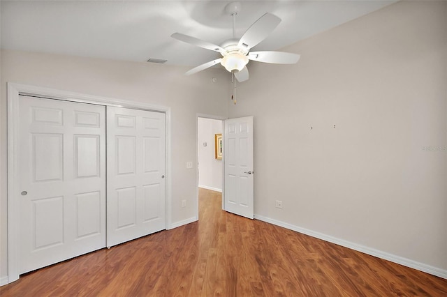 unfurnished bedroom with ceiling fan, wood-type flooring, a closet, and lofted ceiling