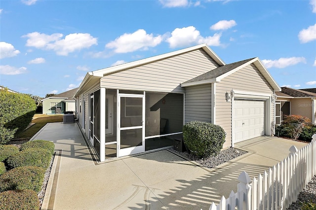 view of front facade featuring central AC, a garage, and a sunroom