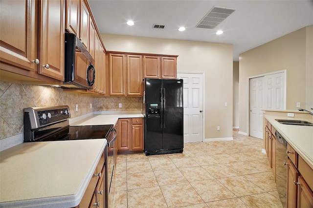 kitchen with sink, light tile patterned floors, backsplash, and black appliances