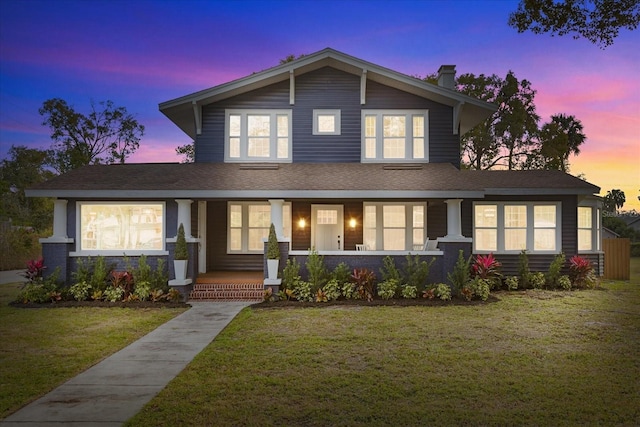 view of front of property with a porch and a lawn