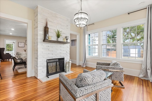 living room featuring light wood-type flooring, a chandelier, and a fireplace