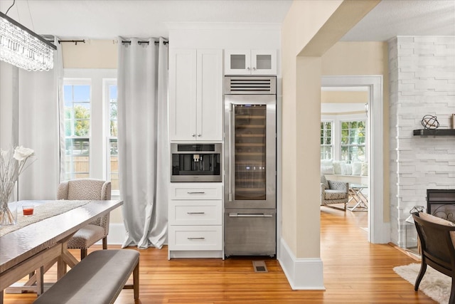 kitchen featuring white cabinets, plenty of natural light, wine cooler, and light hardwood / wood-style flooring