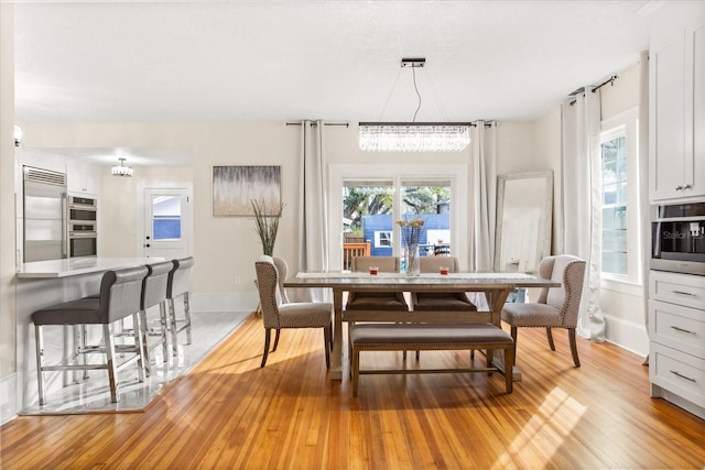 dining space with a notable chandelier and light hardwood / wood-style flooring