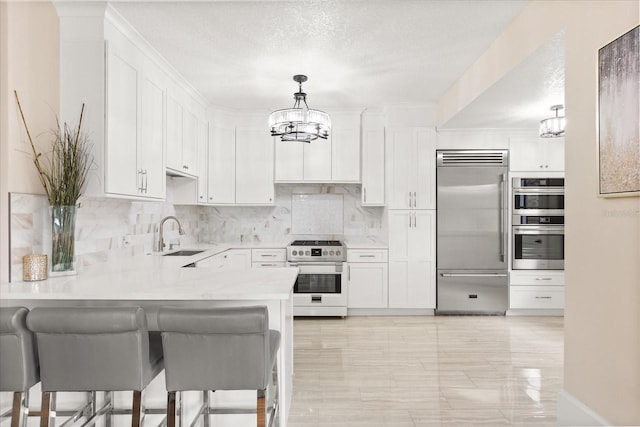 kitchen featuring sink, white cabinets, decorative light fixtures, and premium appliances