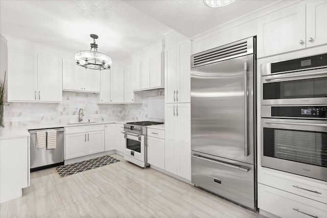 kitchen featuring sink, white cabinetry, decorative backsplash, high quality appliances, and pendant lighting