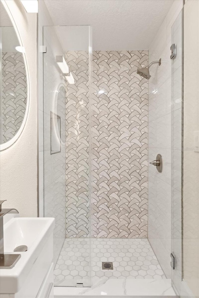 bathroom with a textured ceiling, sink, and a shower with shower door