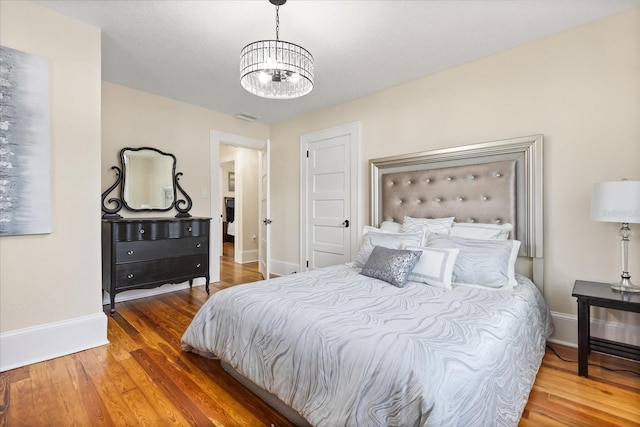 bedroom featuring hardwood / wood-style flooring and an inviting chandelier