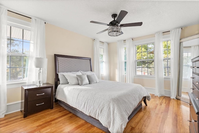 bedroom with ceiling fan, light wood-type flooring, and a textured ceiling