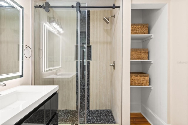 bathroom with hardwood / wood-style flooring, a shower with door, and vanity