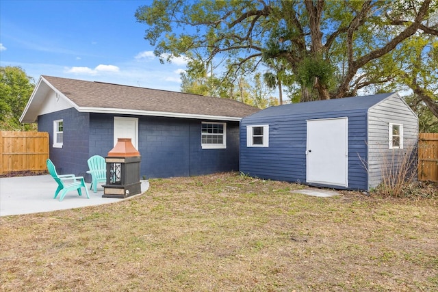 rear view of house featuring a lawn, an outdoor structure, and a patio area