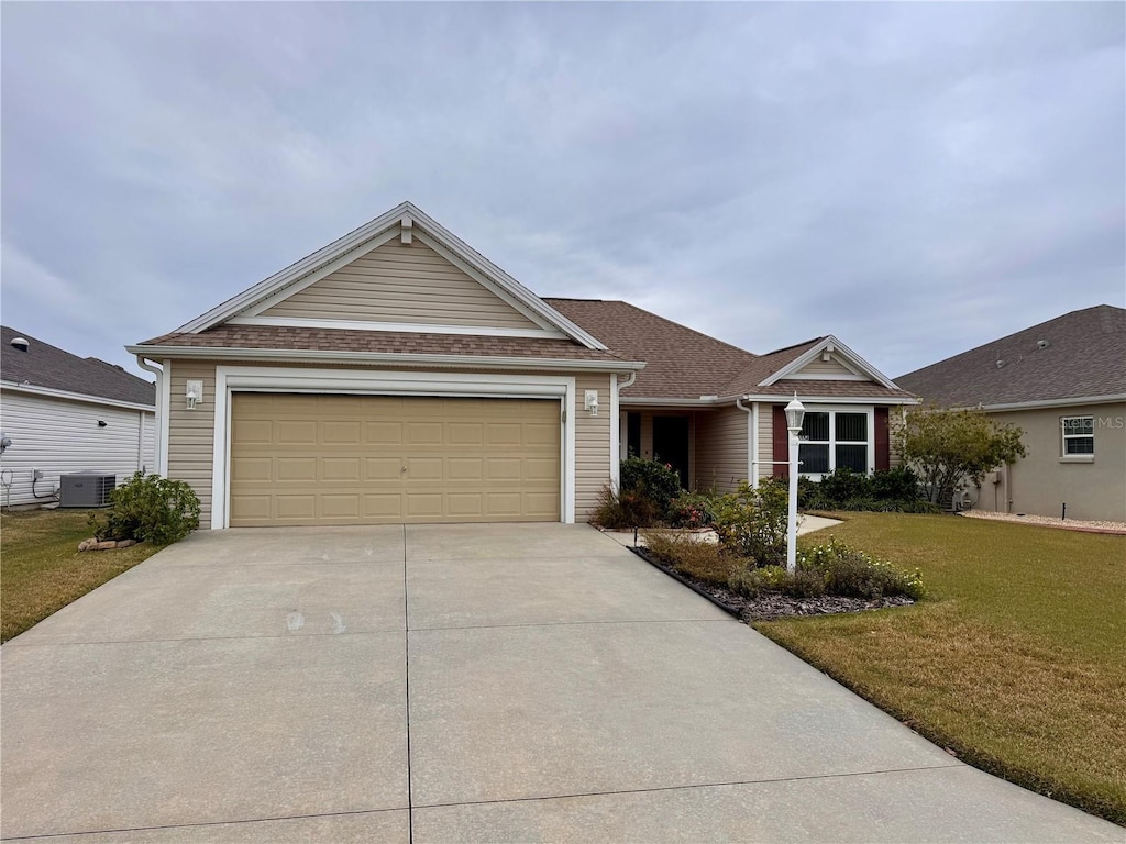 ranch-style home featuring a garage, a front yard, and central AC