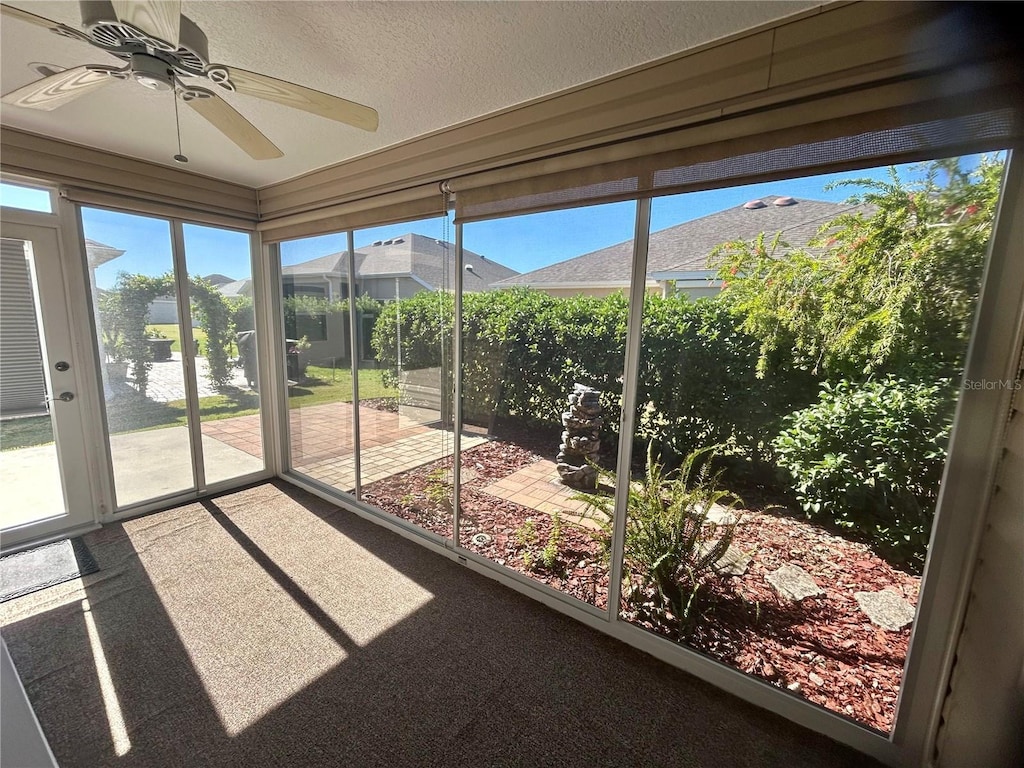 unfurnished sunroom featuring ceiling fan