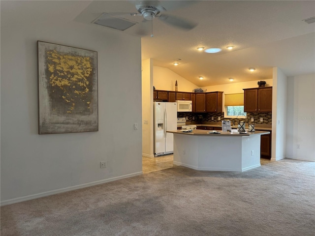 kitchen with white appliances, a center island, vaulted ceiling, ceiling fan, and light colored carpet