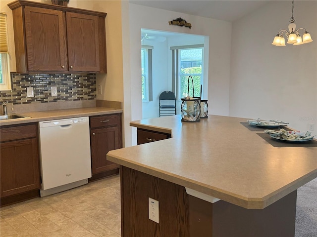 kitchen featuring pendant lighting, kitchen peninsula, a chandelier, and dishwasher