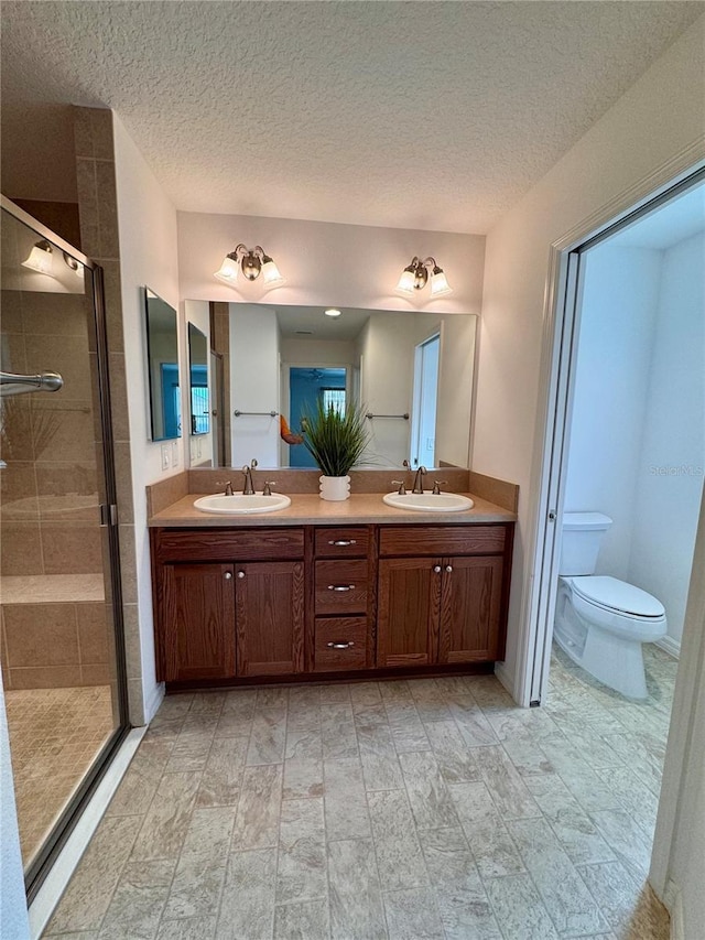 bathroom featuring vanity, walk in shower, a textured ceiling, and toilet