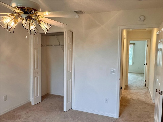 unfurnished bedroom with ceiling fan, light carpet, and a closet