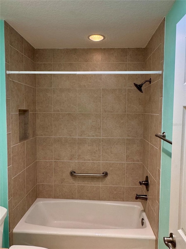 bathroom with toilet, tiled shower / bath combo, and a textured ceiling