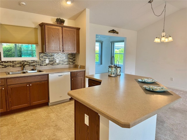 kitchen with decorative backsplash, dishwasher, lofted ceiling, brown cabinets, and a sink