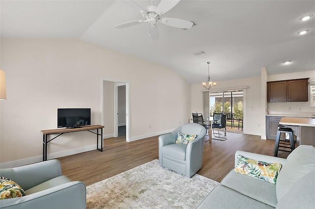 living room with ceiling fan with notable chandelier, dark wood-type flooring, and lofted ceiling