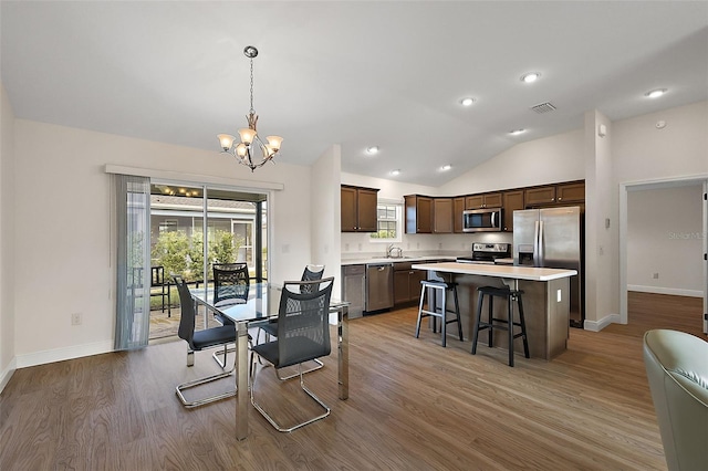 dining space featuring lofted ceiling, sink, a chandelier, and hardwood / wood-style flooring