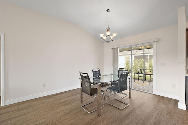 dining room featuring dark wood-type flooring, a notable chandelier, and vaulted ceiling