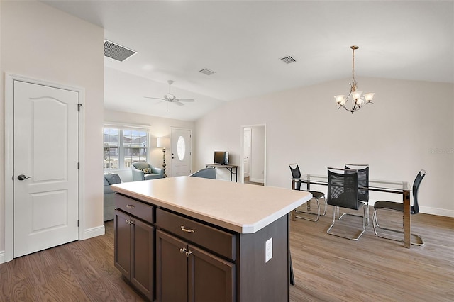 kitchen with lofted ceiling, a center island, wood-type flooring, hanging light fixtures, and dark brown cabinets