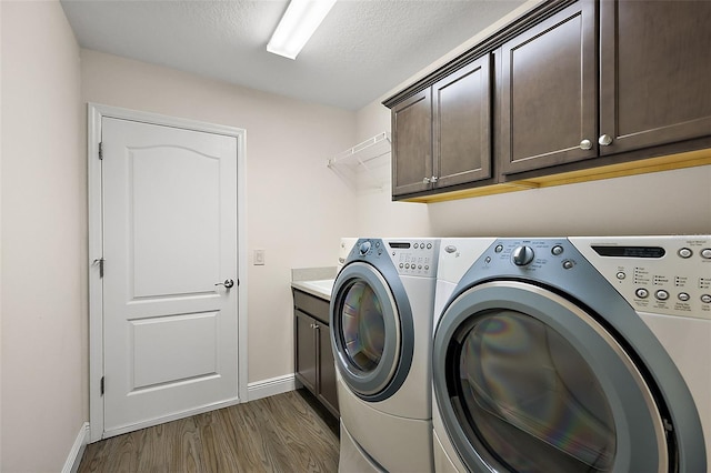 laundry room featuring dark hardwood / wood-style floors, independent washer and dryer, a textured ceiling, and cabinets