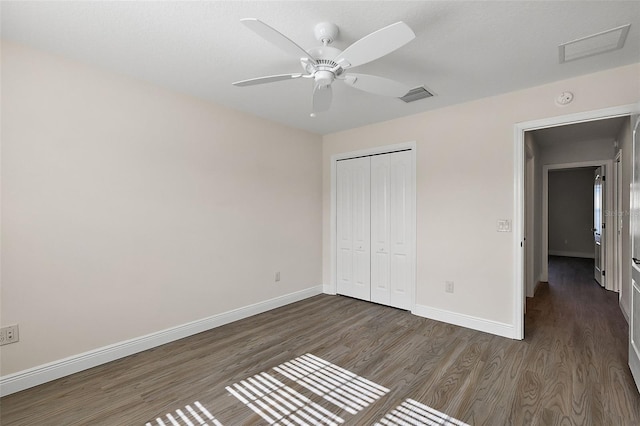 unfurnished bedroom with dark wood-type flooring, a closet, and ceiling fan