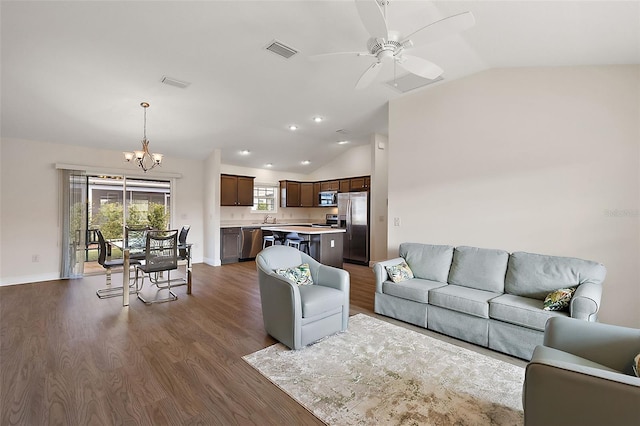 living room with ceiling fan with notable chandelier, sink, dark wood-type flooring, and vaulted ceiling