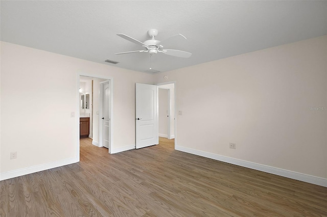 unfurnished bedroom with ceiling fan, ensuite bath, and hardwood / wood-style floors