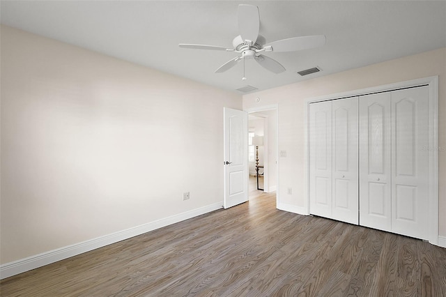 unfurnished bedroom featuring hardwood / wood-style floors, a closet, and ceiling fan