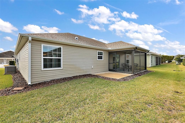 rear view of property featuring a patio, a yard, a sunroom, and central AC