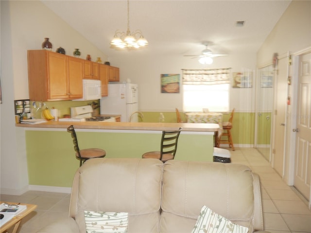 tiled dining space featuring ceiling fan with notable chandelier, sink, and vaulted ceiling