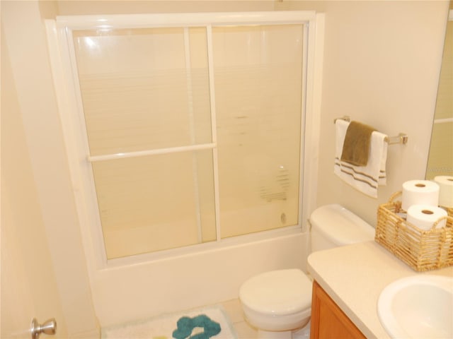 full bathroom featuring toilet, shower / bath combination with glass door, and vanity