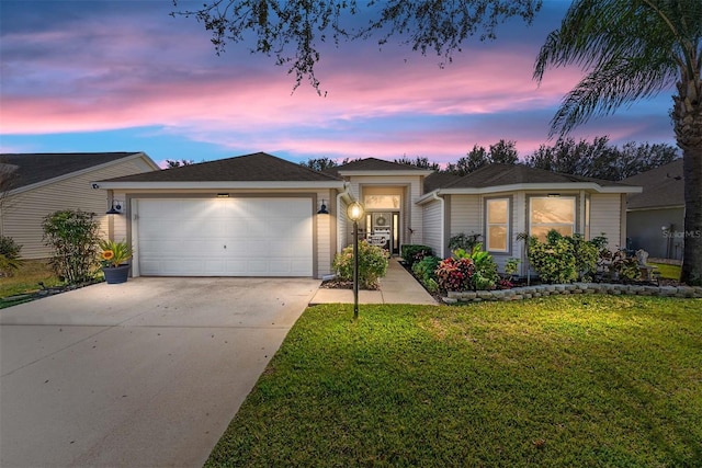 view of front of home featuring an attached garage, concrete driveway, and a yard