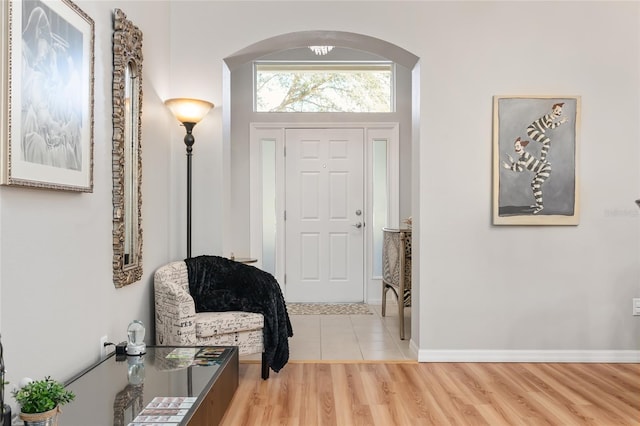 foyer with baseboards, arched walkways, and wood finished floors