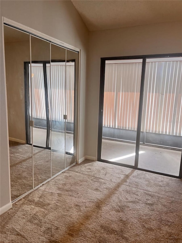 unfurnished bedroom featuring a closet, vaulted ceiling, and carpet flooring