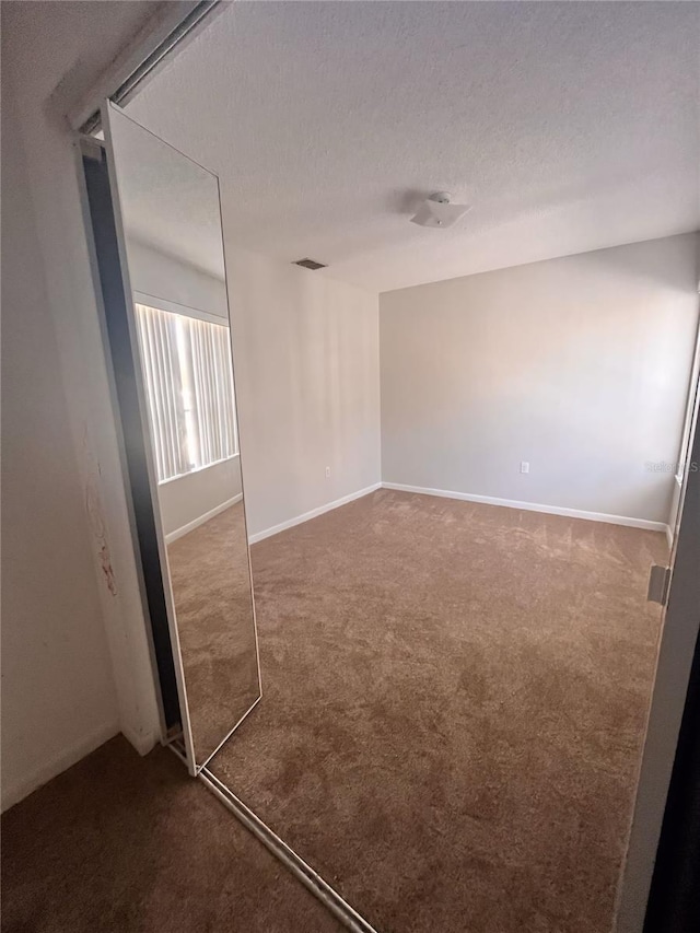 carpeted spare room with a textured ceiling